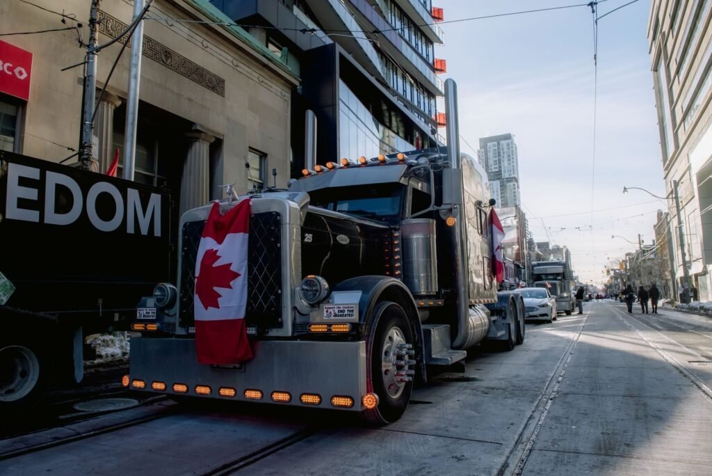 Truck convoy with Canadian flag during protest in downtown street. Demonstration for freedom movement.